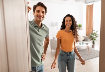 happy young couple inviting into home