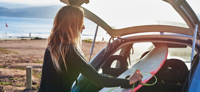 Girl putting surfboard in a car